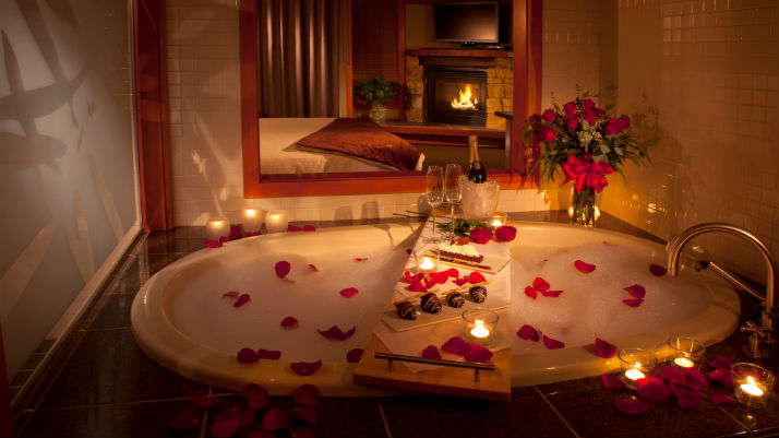 bathtub with rose petals and candlelight