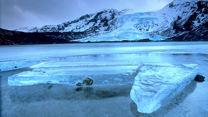 ice formations on lake with mountains behind