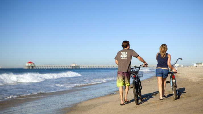 Couple walking bikes on beach