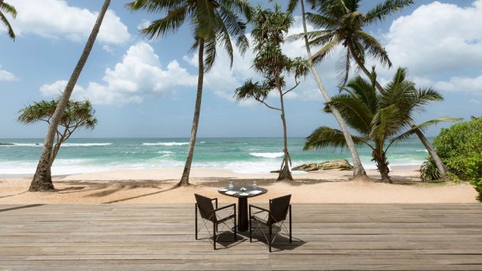 Amanwella Resort's open patio on beach with table and chairs