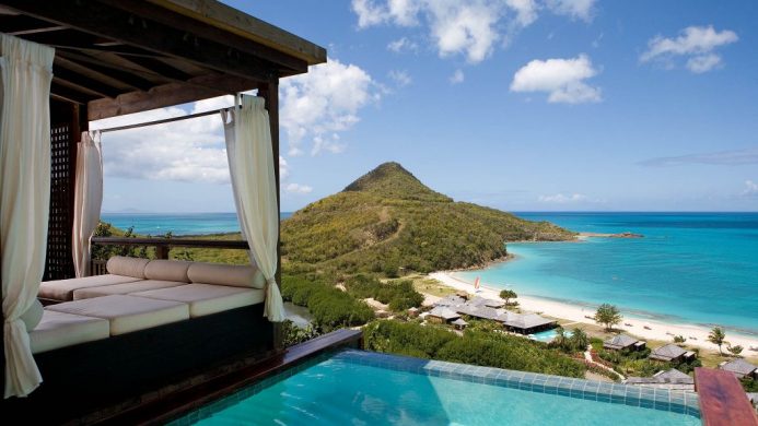 Private pool and lounged perched on hillside overlooking green mountains and sea below