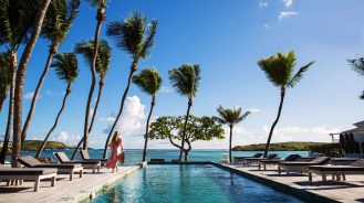Woman standing beside pool looking out to ocean at Le Sereno resort