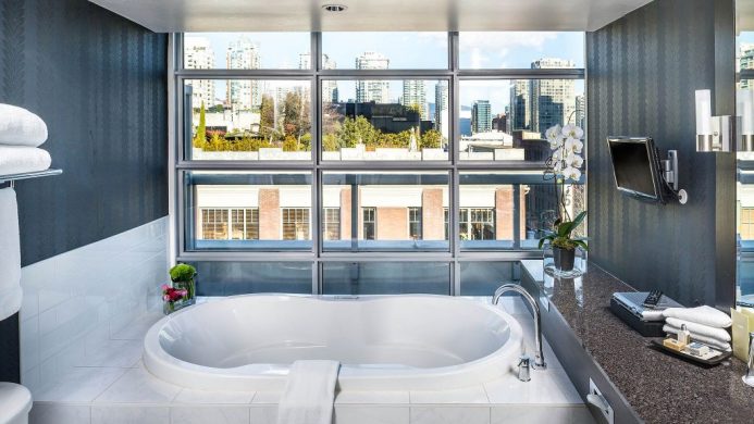 Suite bathroom with windows overlooking city at Opus Hotel Vancouver