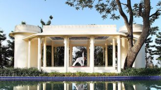 Man doing yoga in a white garden pavilion