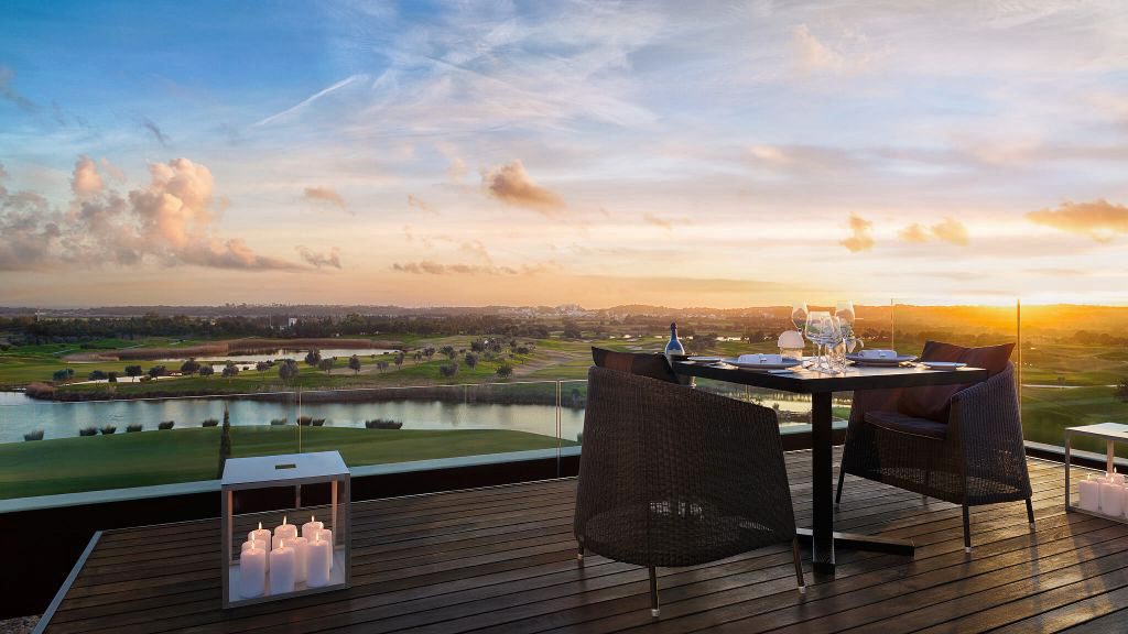 Small dinner table on terrace with candle lights overlooking golf course sunset
