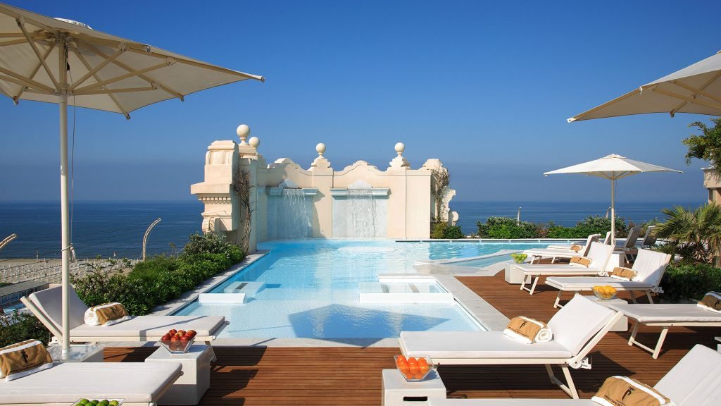 Rooftop pool with waterfall and lounge chairs overlooking the ocean