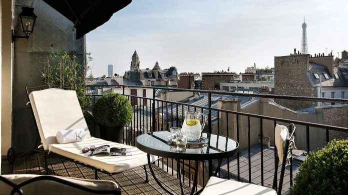 Balcony with patio chair and lounge chairs with view of rooftops and Eiffel Tower