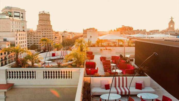 Rooftop with red furniture and plunge pool at sunset