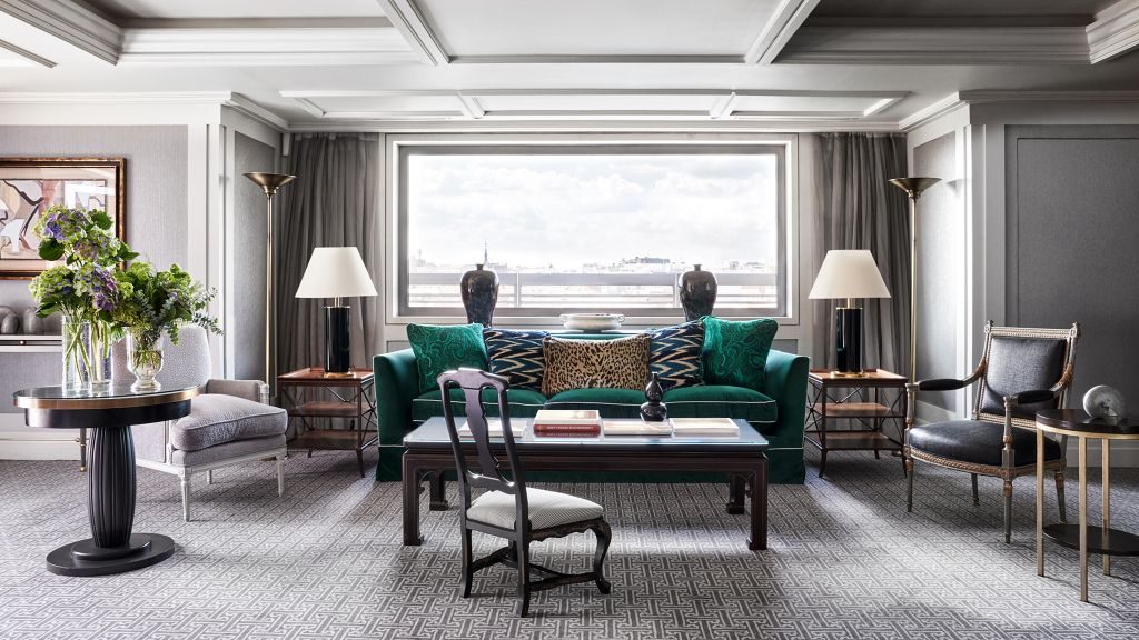 Suite room with large window, crown moulding and elegant grey walls and furniture