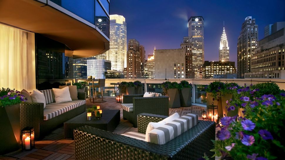 Large patio with lounge furniture and New York's lit up buildings in the background