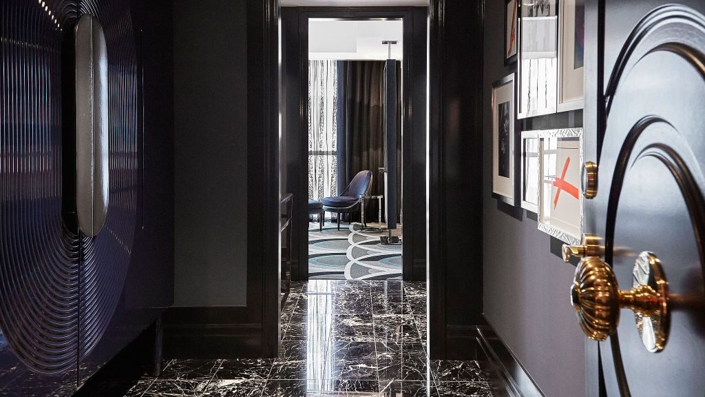 Bisha Hotel room entrance with gold doorknob, black marble tiles and gallery wall