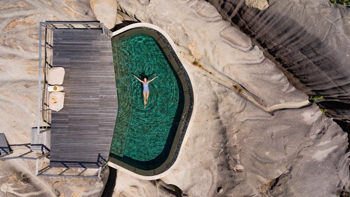 Aerial of woman floating pool over rocks at the SIx Senses Zil Pasyon