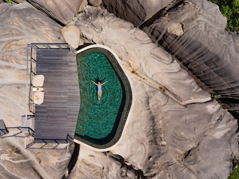 Hotel Spas | Aerial view of woman floating in spa pool on rocks at the Six Senses Zil Pasyon