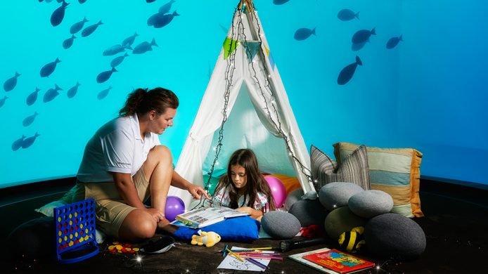 Babysitter and child camping in underwater aquarium at the Conrad Maldives