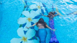 Adult and child swimming with mermaid tails at the Fairmont Kea Lani Maui