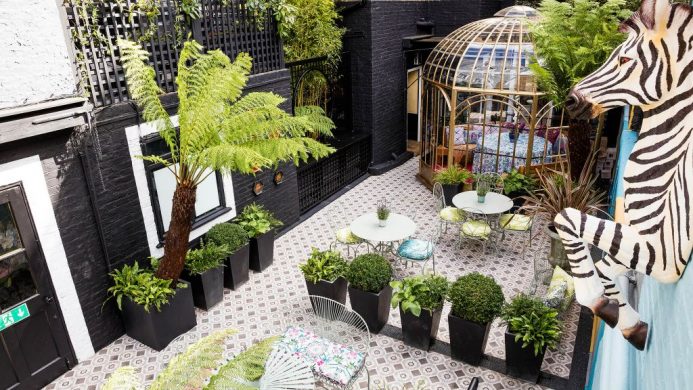 Blakes Hotel London courtyard garden with mosaic tiles, birdcage seating and zebra wall sculpture