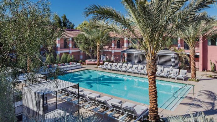 Sands Hotel pool surrounded by palm trees, cabanas and pink buildings