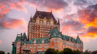 Exterior of Fairmont Le Chateau Frontenac in front of a fiery sky