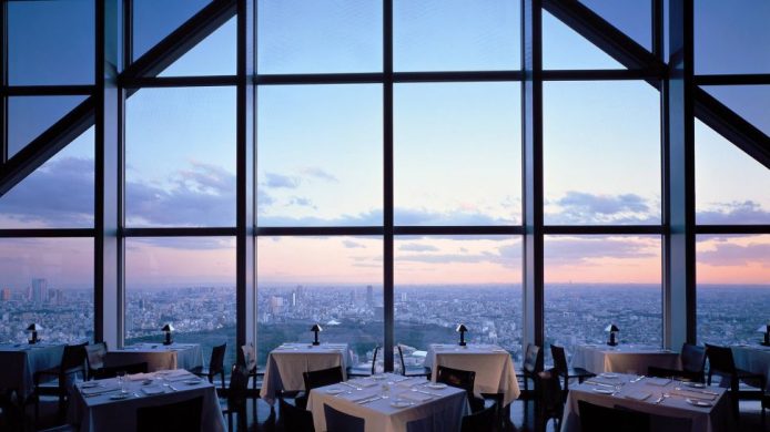 Park Hyatt Tokyo's restaurant dining room with high windows framing city of Tokyo