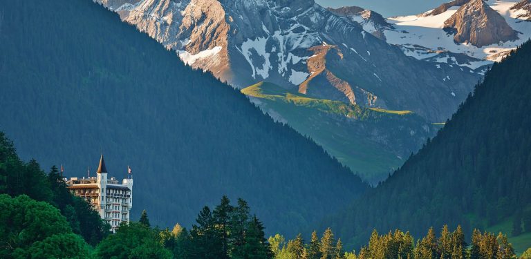 Gstaad Palace's towers peaking out from the forest under the Swiss mountains