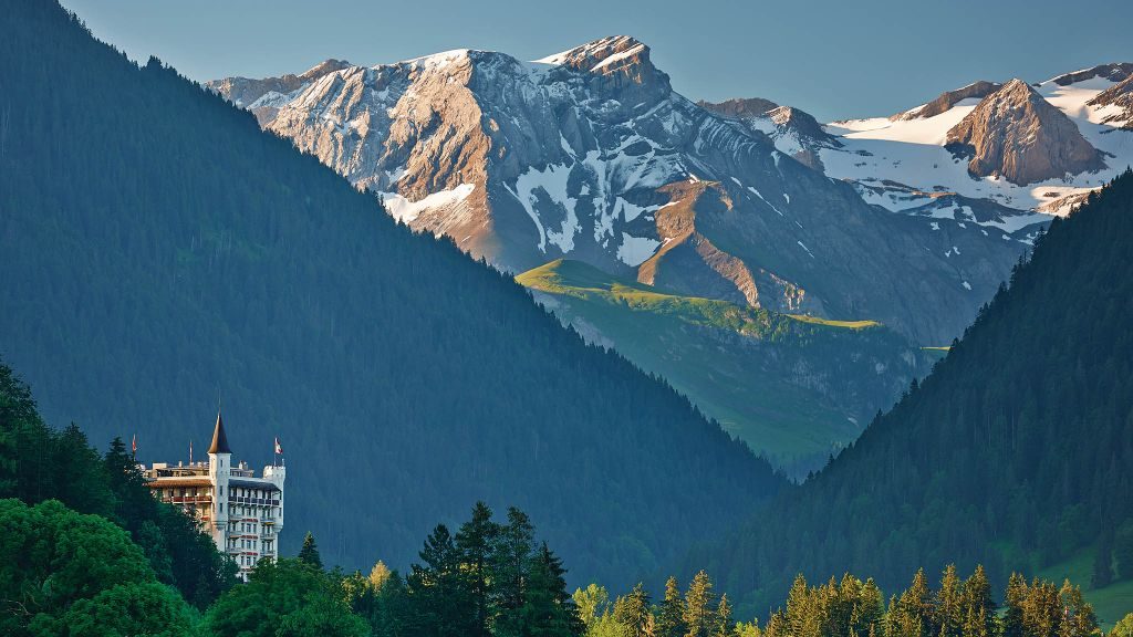 Gstaad Palace's towers peaking out from the forest under the Swiss mountains