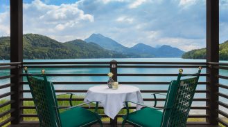 Schloss Fuschl's cottage balcony overlooking a lake and green hills