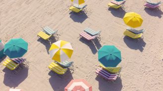 Aerial of candy color beach umbrellas on the beach at The Confidante hotel