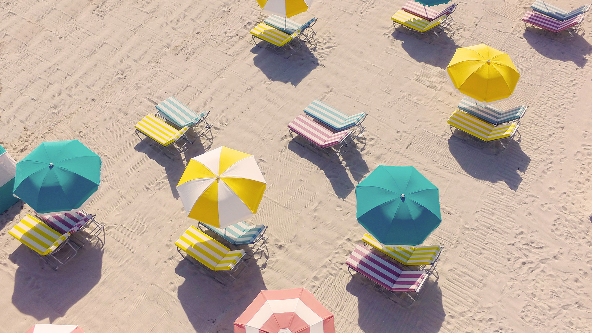 Aerial of candy color beach umbrellas on the beach at The Confidante hotel
