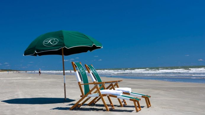 Quiet beach with two hotel-branded beach chairs under an umbrella on Kiawah Island