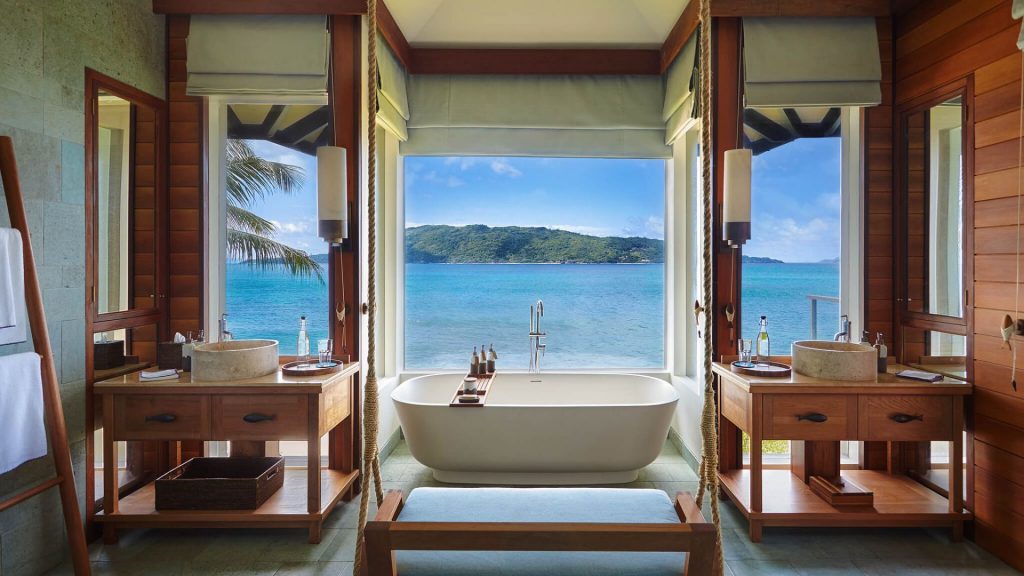 Bathroom at Six Senses Zil Pasyon resort with a bathtub next to a floor-to-ceiling window view of the ocean