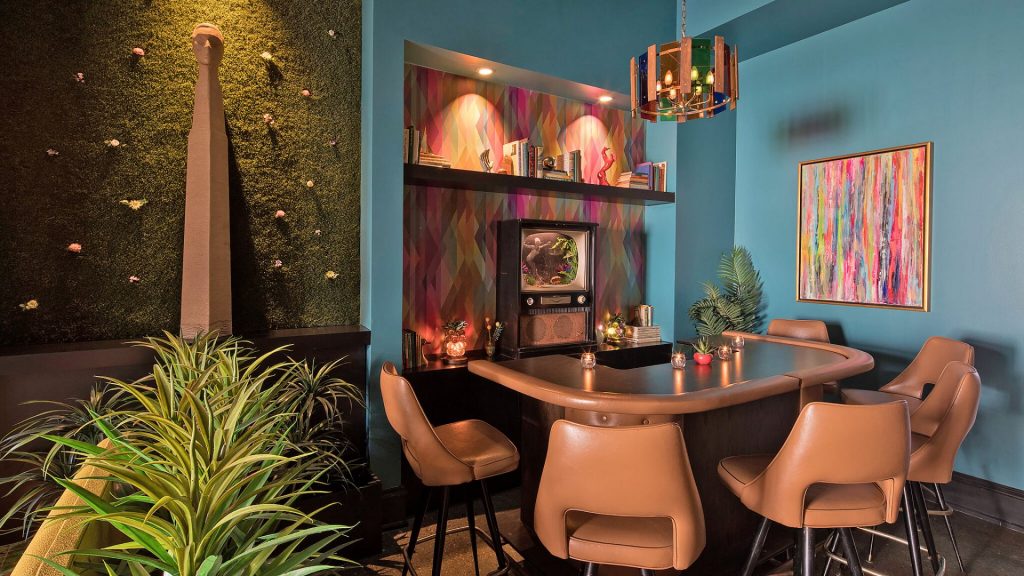 The Dwell Hotel's Rainbow Room Bar with mid-century furniture and a blue wall