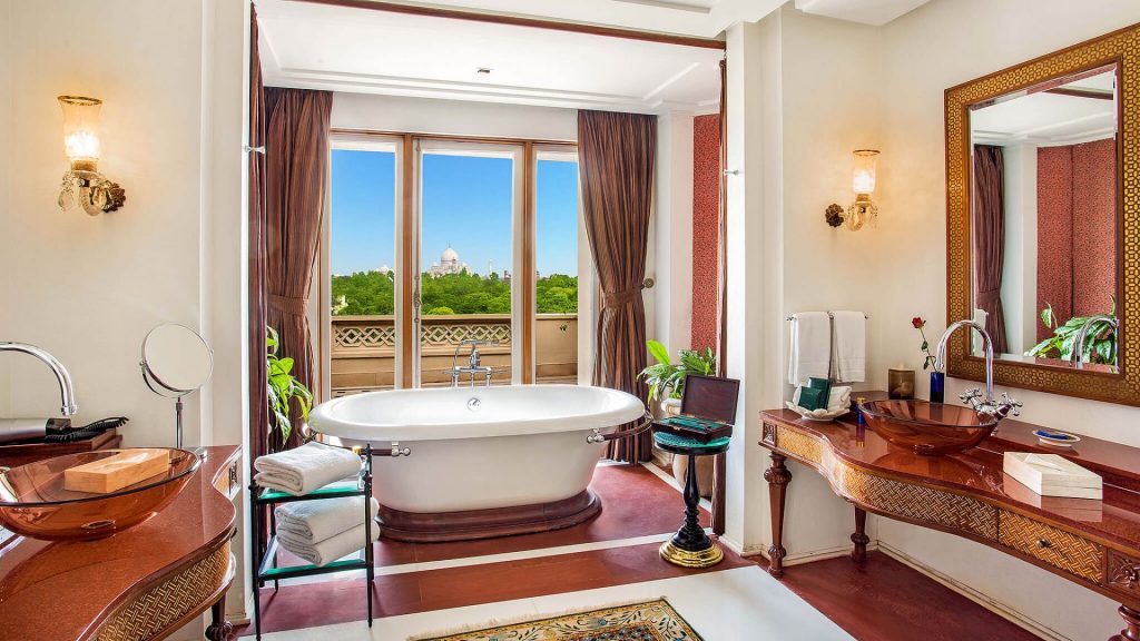 The Oberoi Amarvilâs bathroom with a freestanding tub in front of a curtained window overlooking a far-off view of the Taj Mahal
