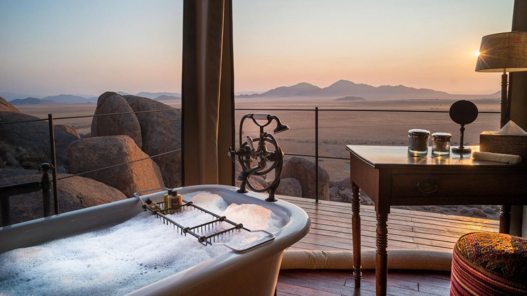 Claw-foot bathtub in an open-air tented suite at Zannier Hotels Sonop, looking out to the sand dunes at dusk
