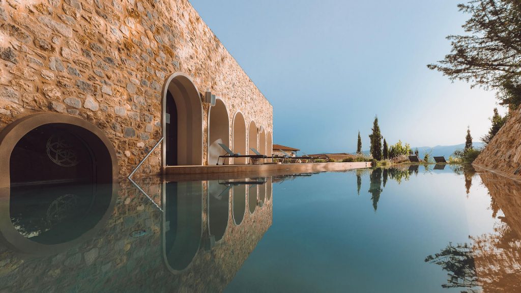 Outdoor pool beside stone wall with arched entries at the Euphoria Retreat