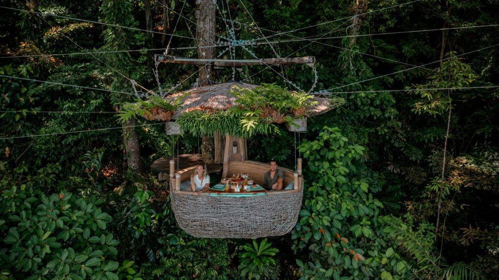 treehouse hotels - Couple sitting in Soneva Kiri's treepod dining pod elevated in the trees
