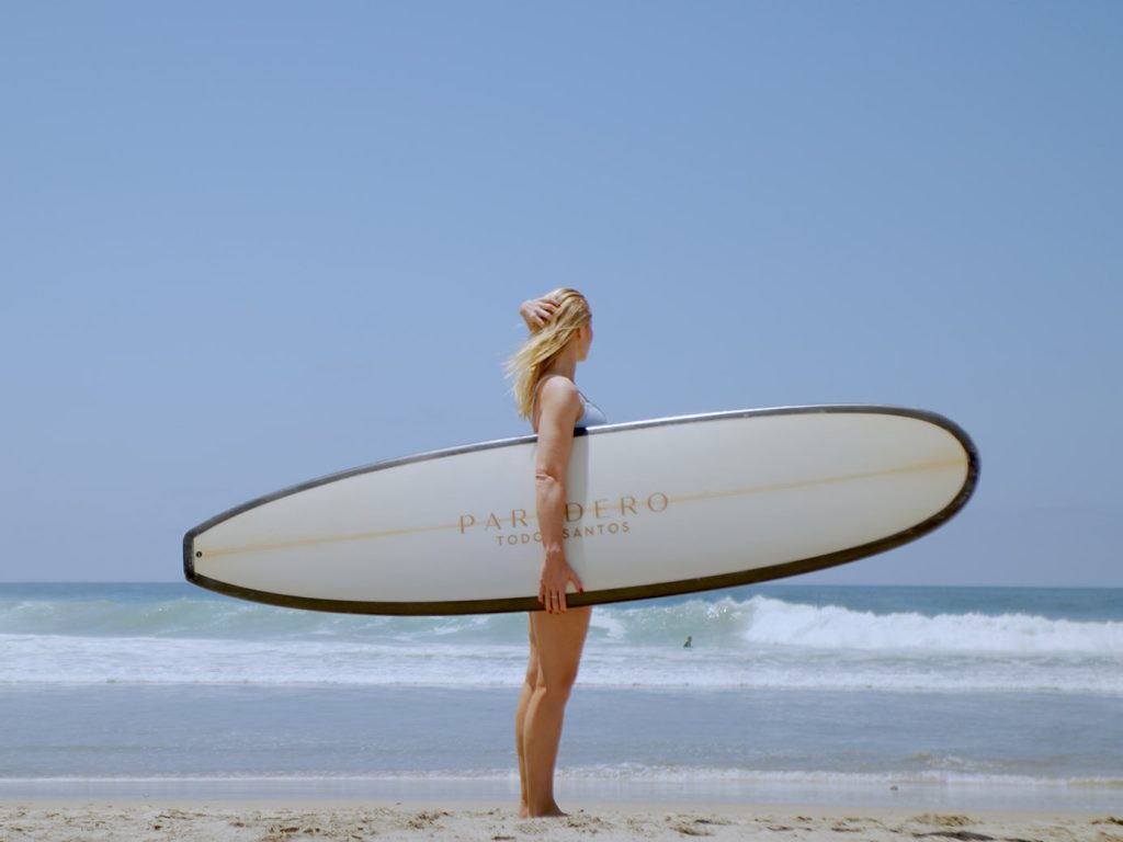 Paradero Todos Santos – woman holding surf board looking out the the sea