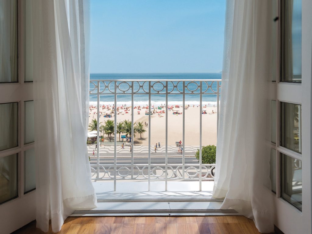Timeless Hotels | A balcony with a view of the beach and ocean at Copacabana Palace, A Belmond Hotel in Rio, Brazil