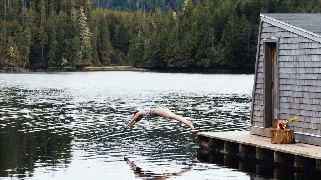 hotels with cold plunges - woman diving from Nimmo Bay's floating sauna dock into the ocean