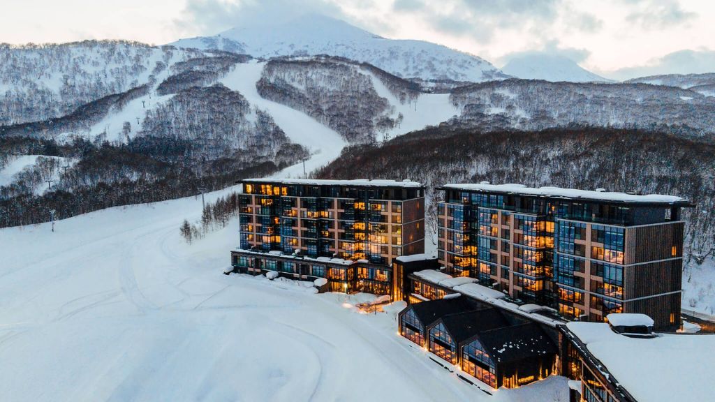 coolest ski resorts - Park Hyatt Niseko Hanazono with lights on it and a snowy mountain