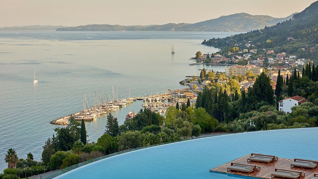 passion travel - Angsana Corfu Resort & Spa - a pool with a body of water and a city in the background
