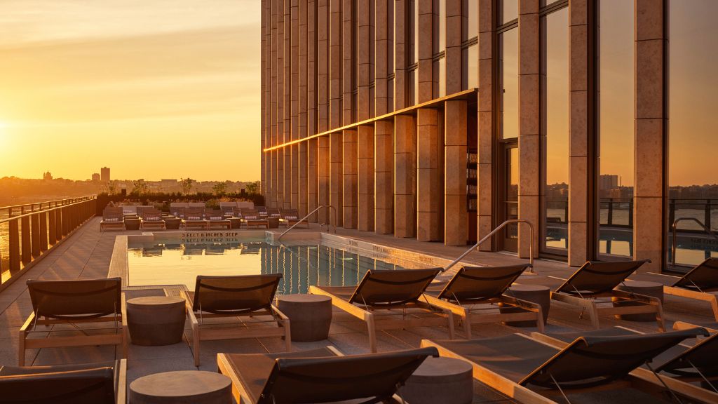 passion travel - Equinox Hotel, Hudson Yards - a pool with lounge chairs and a building in the background