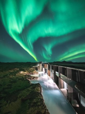 The Retreat at Blue Lagoon | a lagoon next to a hotel suite with Northern Lights in the background