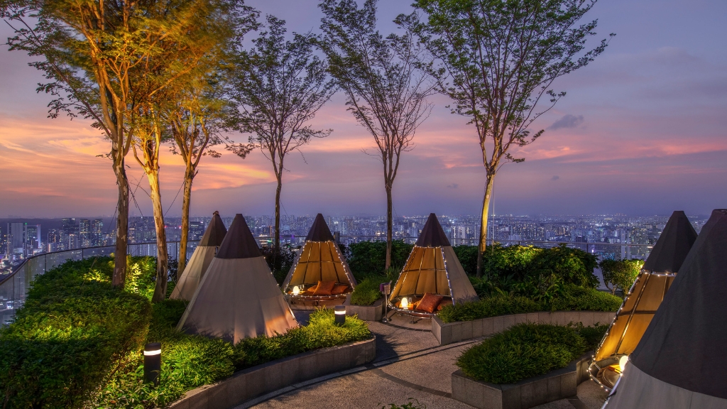 Proposal Hotels - Andaz Singapore - Epicurean Sophisticates - a group of tents with trees and a city in the background