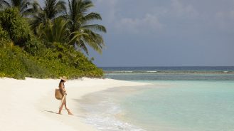 Six Senses Laamu Travel Diary by laurandnicolas- a woman walking on a beach