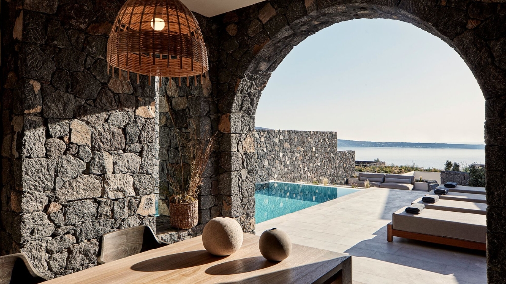 Proposal Hotel - Canaves Oia Epitome - Modern Minimalists - a stone patio with a pool and a stone wall