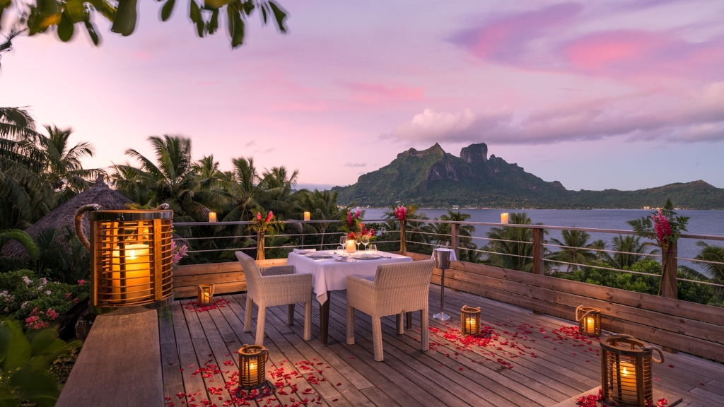 Proposal Hotel - Conrad Bora Bora Nui Island - Escape Artists - a table set up on a deck overlooking a body of water