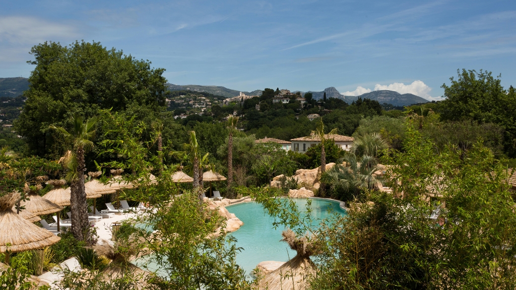 Best hotels in the South of France - Domaine du Mas de Pierre - Saint-Paul-de-Vence - pool surrounded by straw umbrellas and white sunbeds