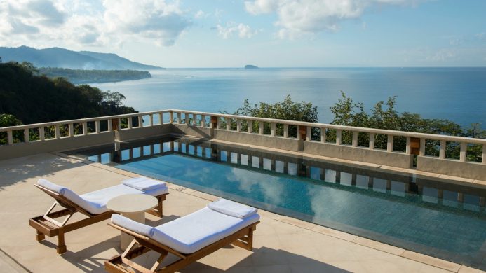 a pool with chairs and tables overlooking the ocean | Private pool suite at Amankila, Indonesia