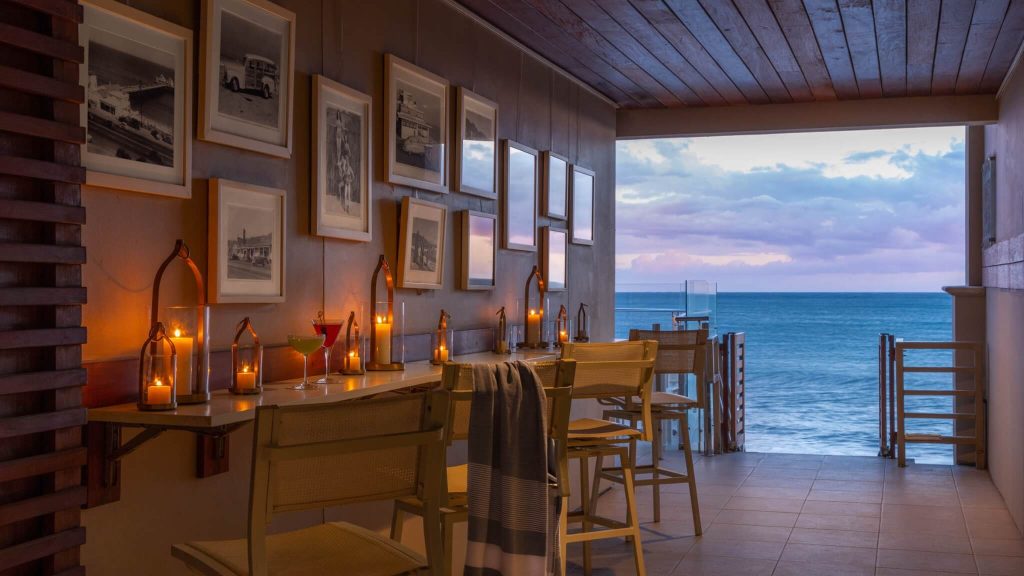 Sunset cocktails at Malibu Beach Inn | Malibu, USA | a breezeway with a table and chairs and a view of the ocean at sunset