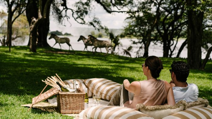 Picnic spots - The Royal Livingstone Victoria Falls Zambia Hotel by Anantara - Victoria Falls, Zambia - two people sitting on a picnic blanket looking at zebras